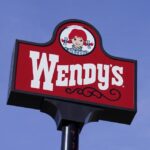 A sign for Wendy’s restaurant stands over one of its locations, Feb. 25, 2021, in Des Moines, Iowa.