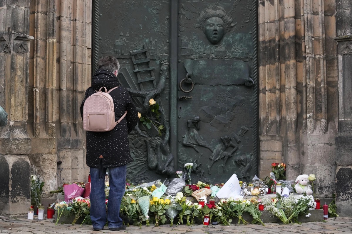 A person stands by flowers and candles placed outside St. John’s Church near a Christmas Market, where a car drove into a crowd on Friday evening, in Magdeburg, Germany, Saturday, Dec. 21, 2024. 