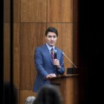 Canada’s Prime Minister Justin Trudeau is pictured through glass as he speaks with members of his caucus in Ottawa, Ontario, on Monday, Dec. 16, 2024.