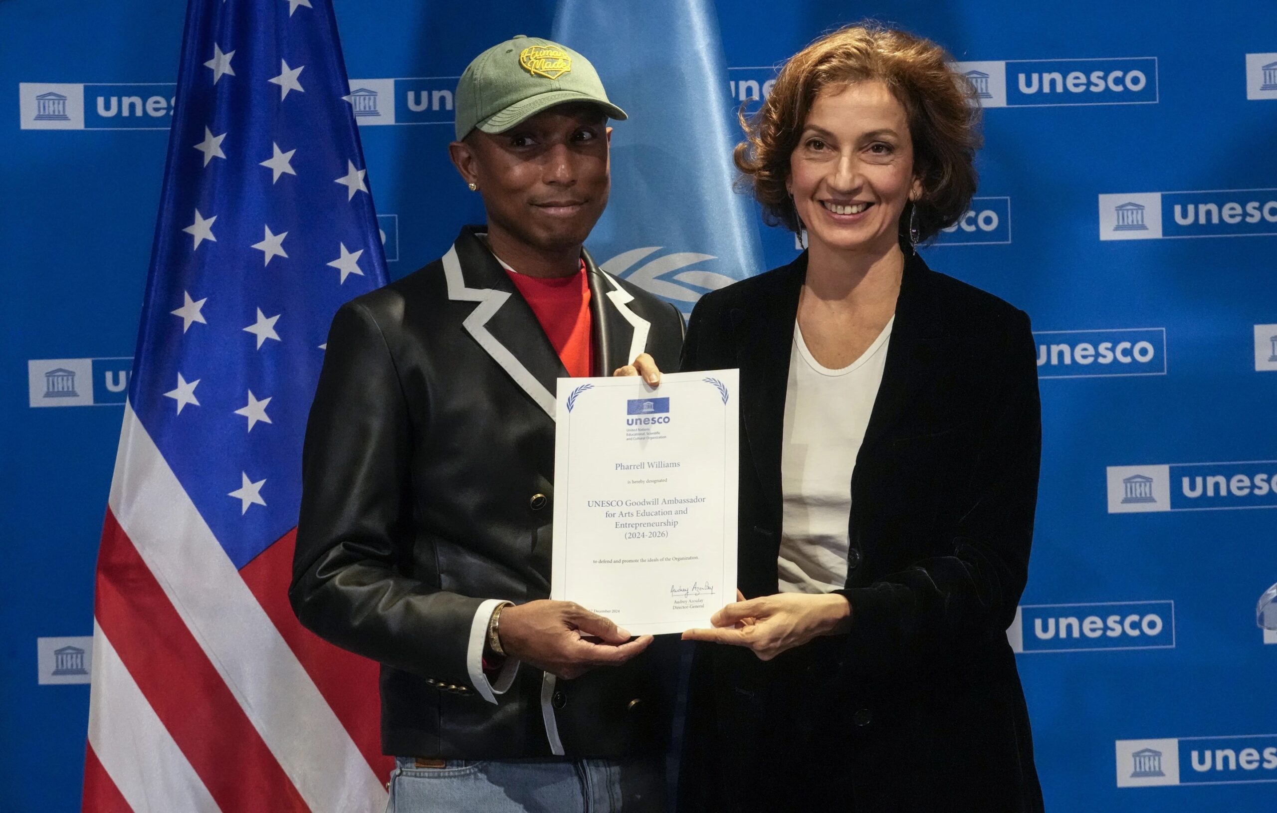 Pharrell Williams, left, holds his diploma of Goodwill Ambassador for for Arts, Education and Entrepreneurship as he poses with UNESCO Director General Audrey Azoulay at UNESCO headquarters in Paris, Tuesday, Dec. 17, 2024. 