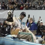 Rapper Snoop Dogg, center, arrives with the trophy after Miami (Ohio) defeated Colorado State in the Arizona Bowl NCAA college football game, Saturday, Dec. 28, 2024, in Tucson, Ariz.