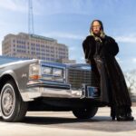 Tiff Massey poses with a Cadillac to promote her exhibition about metalsmithing, jewelry and the city’s streets.