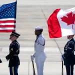 An honour guard stands with U.S. and Canadian flags in July 2024 as they wait for Canadian Prime Minister Justin Trudeau to arrive at Andrews Air Force Base, Md., to attend the NATO summit in Washington.