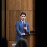 Canada’s Prime Minister Justin Trudeau is pictured through glass as he speaks with members of his caucus in Ottawa, Ontario, on Monday, Dec. 16, 2024.