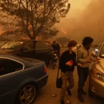 People flee from the advancing Palisades Fire, by car and on foot, in the Pacific Palisades neighborhood of Los Angeles Tuesday, Jan. 7, 2025.