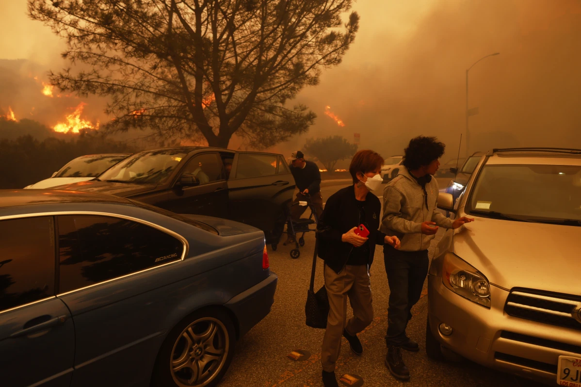 People flee from the advancing Palisades Fire, by car and on foot, in the Pacific Palisades neighborhood of Los Angeles Tuesday, Jan. 7, 2025. 