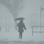 A person holds an umbrella as they walk during a winter storm, Monday, Jan. 6, 2025, in Cincinnati.